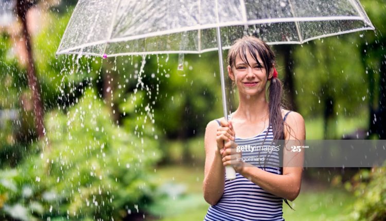 Smiling teenage girl is holding umbrella in rain.Nikon D810