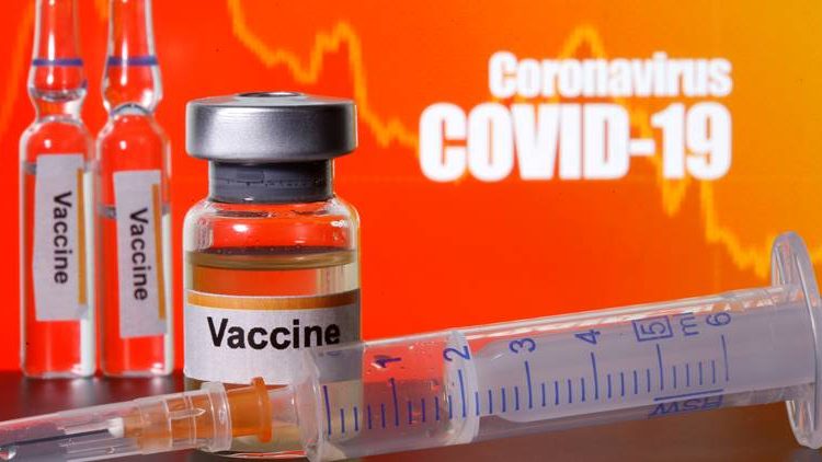 FILE PHOTO: Small bottles labelled with “Vaccine” stickers seen near a medical syringe in front of displayed “Coronavirus COVID-19” words in this illustration